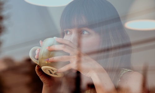 Woman drinking coffee in the window of a coffee shop.