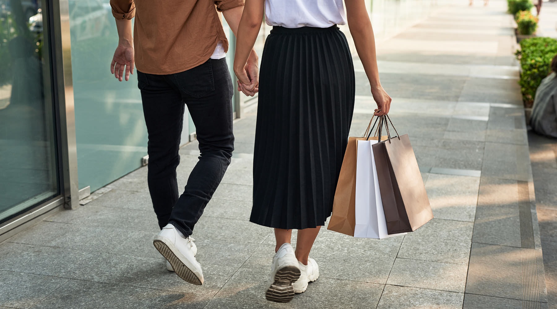 FALL INTO ORBIT couple walks hand-in-hand down sidewalk